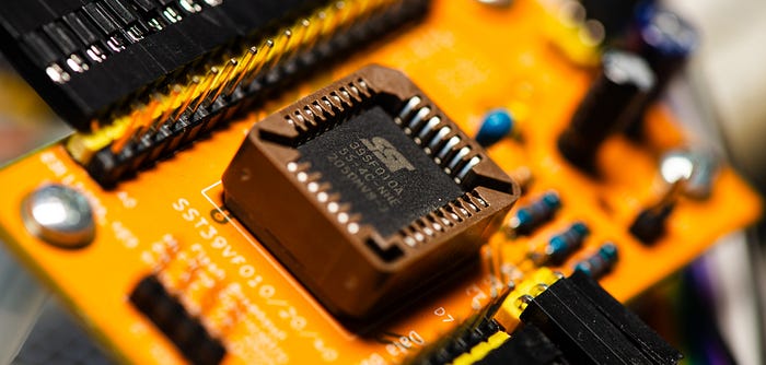 Close-up photograph of a square IC chip in a socket on a yellow circuit board.