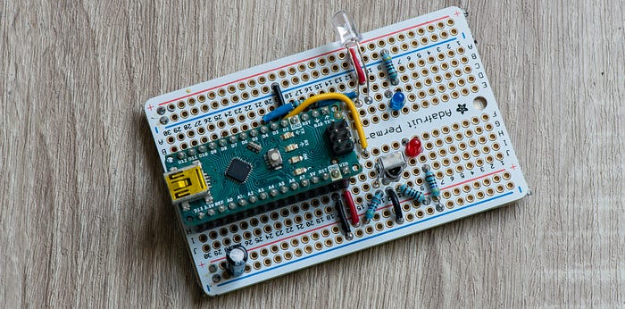 Close-up photograph of an electronics circuit laid out on a prototyping board into which are soldered a microcontroller development board, LEDs and a sensor.