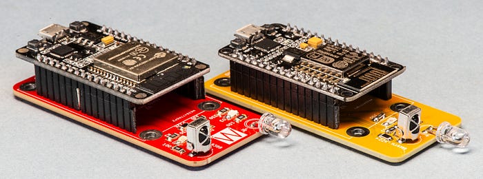 Photograph of two PCB boards (one red, one yellow) with microcontroller developer boards mounted on them.
