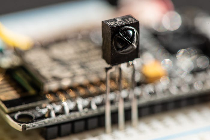 Close-up photograph of a sensor package that has three legs plugged into a prototyping board.