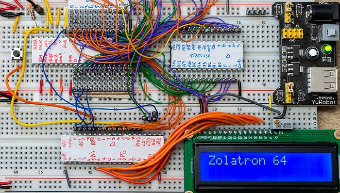 Close-up photograph of an electronics prototyping breadboard into which are plugged chips and wires and an LCD screen.