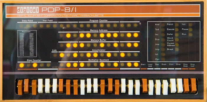Photograph of the front panel of an old computer showing several rows of lights and a large row of switches.