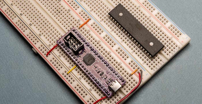 Close-up photograph of a prototyping breadboard with (left) a PCB with header pins and (right) a standard 40-pin DIP chip.