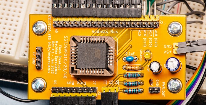 Close-up photograph of a yellow circuit board with a large square chip near the centre.