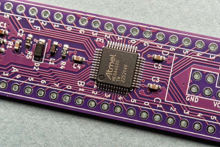 Close-up photograph of a printed circuit board with a square chip labelled ‘Atmel MEGA4809’.