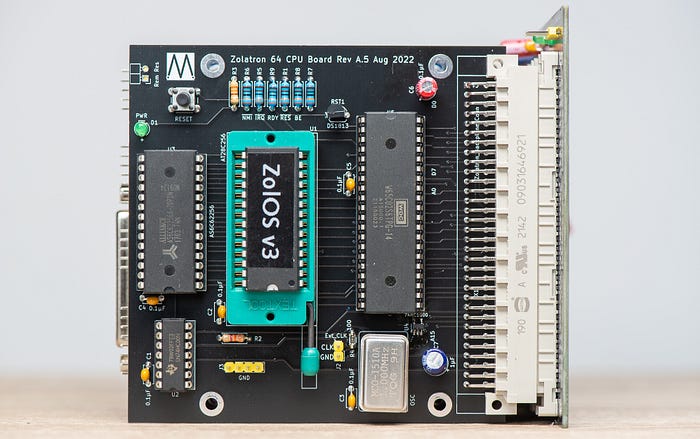 Close-up photograph of an electronics circuit board. Near the centre is a chip marked ‘ZolOS v3’ which is mounted in a turquoise zero insertion force socket.