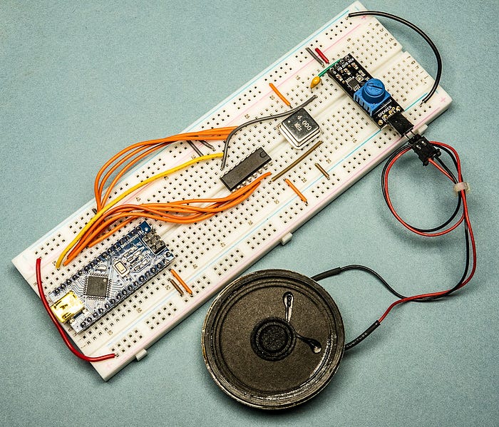 Close-up photograph of an electronics prototyping board wired to a small speaker.