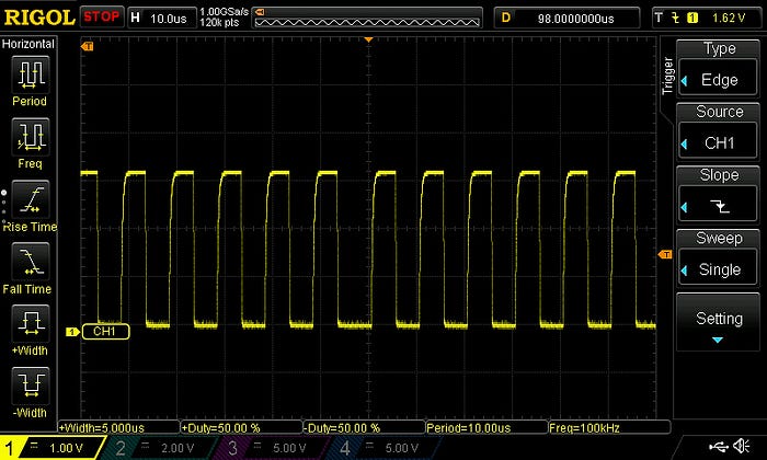 Photograph of an oscilloscope screen showing a regular clock pulse.