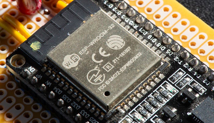 Close-up photographer of a microcontroller development board showing the metal can over the microcontroller chip. We can see the words ‘WiFi’ and ‘ESP-WROOM-32’.
