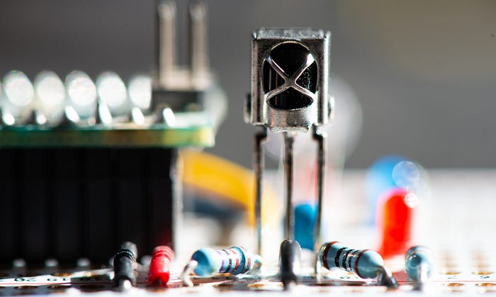 Close-up photograph of a sensor package that has three legs soldered into a prototyping board.