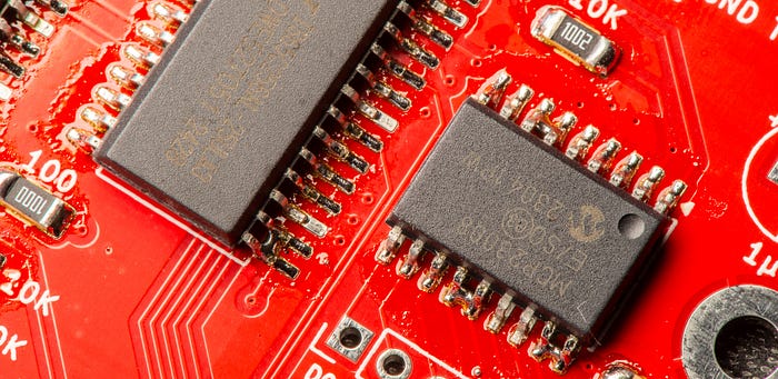 Close-up photograph of two chips on a PCB. There are visibly solder bridges between some of the pins.