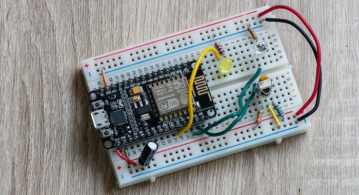 Close-up photograph of an electronics circuit laid out on a prototyping breadboard into which are plugged a microcontroller development board, LEDs and a sensor.